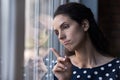 Frustrated unhappy young hispanic woman looking out of window.