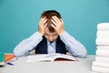 Frustrated upset boy at school sitting at the desk and dotng classwork.