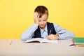 Frustrated upset boy at school sitting at the desk and dotng classwork.