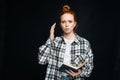 Frustrated upset young woman college student holding book and looking at camera on black background. Royalty Free Stock Photo