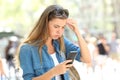 Frustrated woman reading phone content in the street