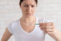 Frustrated woman shows a positive pregnancy test. Child free concept. Human chorionic gonadotropin. Two stripes