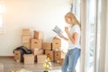 Frustrated woman standing by cardboard boxes in new house near window Royalty Free Stock Photo