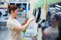 A frustrated woman uses a self-checkout counter. The girl does not understand how to independently buy groceries in the Royalty Free Stock Photo