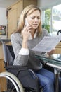 Frustrated Woman In Wheelchair Making Phone Call Whilst Reading Royalty Free Stock Photo