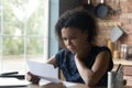 Frustrated young african american woman reading letter with bad news. Royalty Free Stock Photo