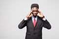 Frustrated young African man holding fingers on head and looking at camera while standing against grey background Royalty Free Stock Photo