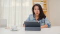 Frustrated Young Asia lady having problem with not working tablet computer sitting on desk. Royalty Free Stock Photo