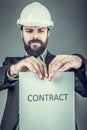 Frustrated young engineer with hardhat tearing apart a contract Royalty Free Stock Photo