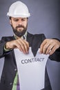 Frustrated young engineer with hardhat tearing apart a contract Royalty Free Stock Photo