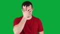 frustrated young guy in a red t-shirt hears bad news, puts his hand to his face, nods negatively on a green screen