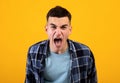 Frustrated young guy shouting in anger, expressing his fury over orange studio background. Negative emotions concept Royalty Free Stock Photo