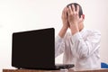 Frustrated young man, holding his head in front of a laptop in t Royalty Free Stock Photo