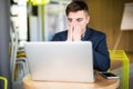 Frustrated young man massaging his nose and keeping eyes closed while sitting at his working place in office Royalty Free Stock Photo