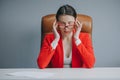 Frustrated young woman keeping eyes closed while sitting at her working place in office. Businesswoman is tired and Royalty Free Stock Photo