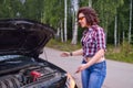 Frustrated young woman looking at broken down car engine Royalty Free Stock Photo