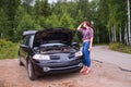 Frustrated young woman looking at broken down car engine Royalty Free Stock Photo