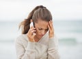 Frustrated young woman in sweater on beach talking cell phone Royalty Free Stock Photo