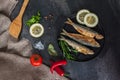 Fry sardines. roast, broi, grill fish on cast-iron frying pan with vegetables and spices around