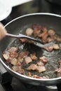 Frying bacon in oily pan