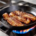 Frying bacon strips on a pan over the stove Royalty Free Stock Photo