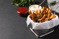 Frying basket with sweet potato fries and sauces on black table. Space for text Royalty Free Stock Photo