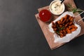 Frying basket with sweet potato fries and sauces on black table, top view. Space for text Royalty Free Stock Photo