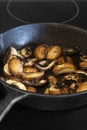Frying chestnut mushrooms in a cast iron frying pan, on an electric stove Royalty Free Stock Photo