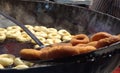 Frying Donuts in hot oil by a iron carrier in a village fair