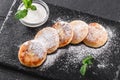 Frying homemade cottage cheese pancakes syrniki with powdered sugar, sour cream.