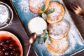 Frying homemade cottage cheese pancakes syrniki with powdered sugar, sour cream, berries jam on plate close up