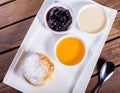 Frying homemade cottage cheese pancakes syrniki with powdered sugar, sour cream, berries jam on plate close up.