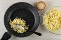 Frying pan with with blend of eggs, chopped cabbage and flour, spoon, bowls with sesame, bowl with vegetable dough on table. Top