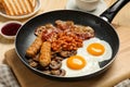 Frying pan with cooked traditional English breakfast on wooden table, closeup Royalty Free Stock Photo