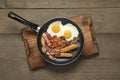 Frying pan with cooked traditional English breakfast on wooden table, top view Royalty Free Stock Photo