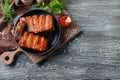 Frying pan with delicious ribs on wooden table