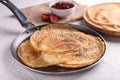 Frying pan with delicious thin pancakes on table