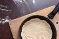A frying pan with dough standing on a cutting board