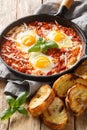 Frying pan with eggs in purgatory on wooden background. Vertical