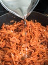 Frying pan with fried carrots. Water flowing