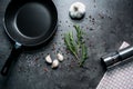 Frying pan with garlic and pepper on black background.