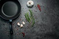 Frying pan with garlic and pepper on black background.