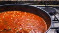 A frying pan on a gas stove, tomato sauce with herbs for pasta or pizza is prepared.