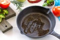 Frying pan made of cast iron, various fresh vegetables and spices on a white wooden kitchen table. Culinary background