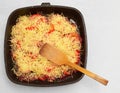 Frying pan with meat, tomatoes, grated cheese, wooden turner closeup
