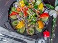 Frying pan with meat and vegetables on a served table top view close-up Royalty Free Stock Photo