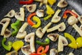 Frying Pan with mushrooms and vegetables. Roasting colorful bell peppers with champignons slices Royalty Free Stock Photo