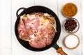 Frying pan with piece of raw meat with spices on white wooden table