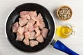 Frying pan with raw chicken breast, bowl with condiment, bottle with vegetable oil on wooden table. Top view Royalty Free Stock Photo