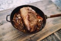 Frying pan with roast beef with vegetables stands on a wooden table Royalty Free Stock Photo